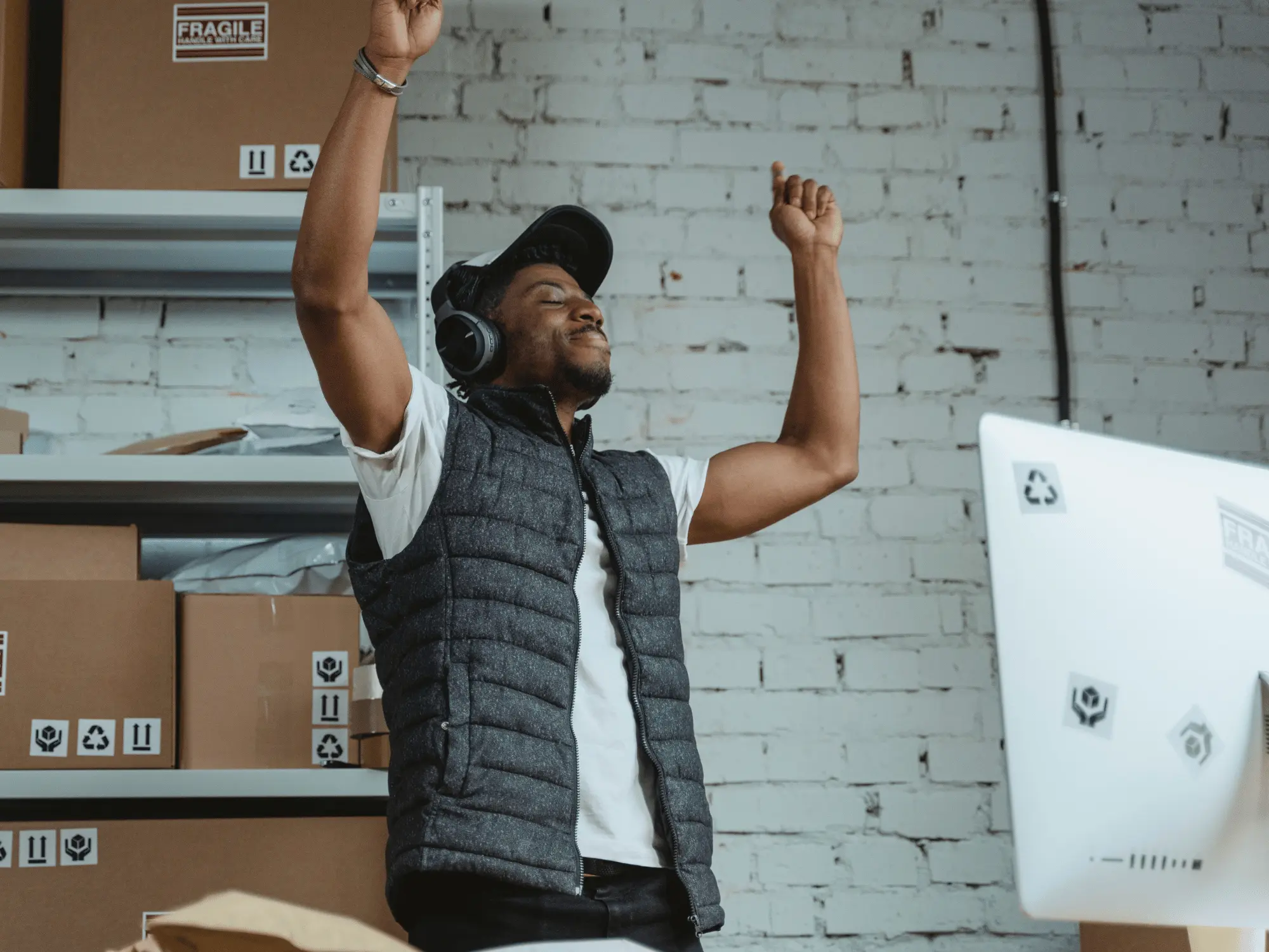 A small-business owner celebrating with arms raised in their shipping room