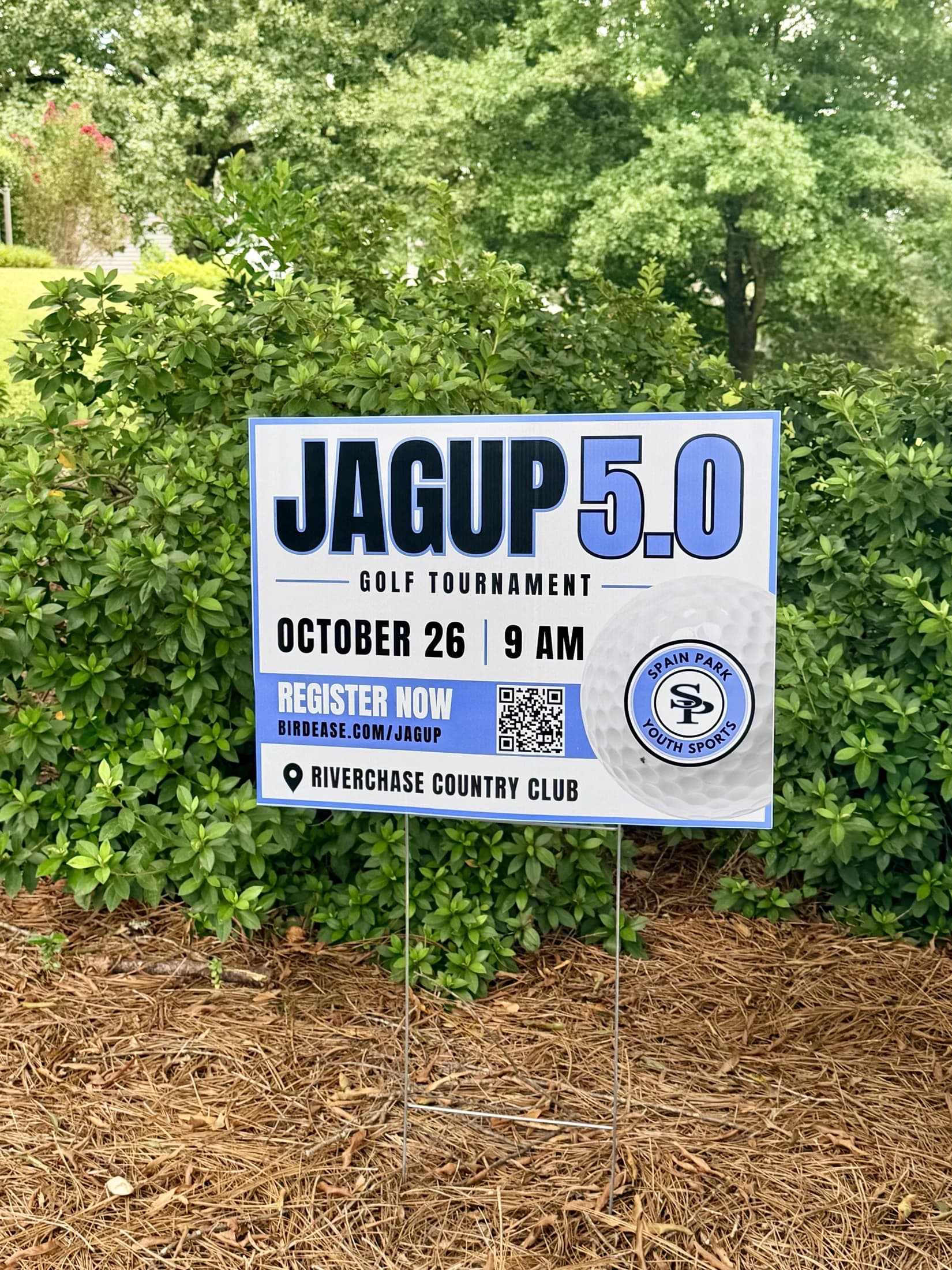A printed 'JagUp 5.0 Golf Tournament' yard sign staked outdoors, designed for Spain Park Youth Sports