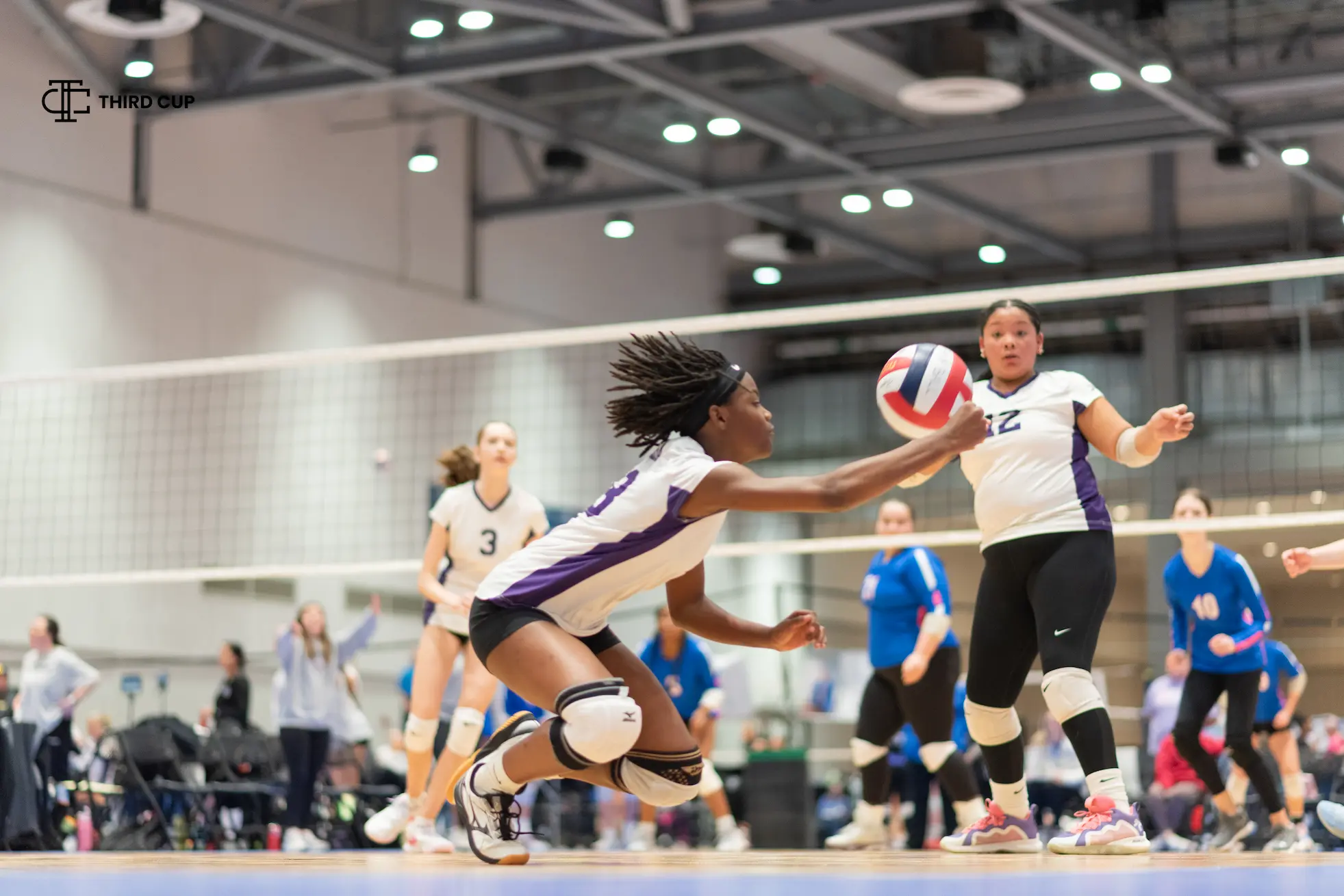 A club volleyball player diving to dig the ball during a tournament rally
